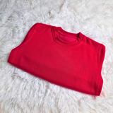 Folded Red Jumper on white fluffy blanket