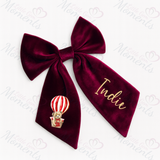 Personalised Wine Velvet Bow with Valentine's Teddy Bear Hot Air Balloon design with name "Indie" on plain white background.