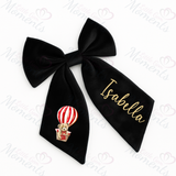 Black hair bow with a teddy bear in a hot air balloon design and 'Isabella' text on a white background.