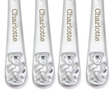 Four silver spoons with teddy bear design and 'Charlotte' engraving on a white background