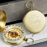 Gold pocket compass with engraved message on a wooden surface