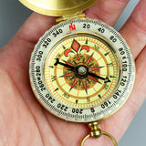 Close-up of a decorative compass held in a hand with a neutral background