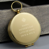 Gold compass with engraved message on a wooden surface