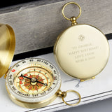 Gold pocket compass with engraved message on a wooden surface