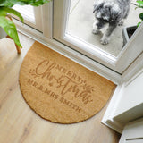 Round doormat with 'Merry Christmas Mr & Mrs Smith' text on a wooden floor, with a dog looking through a glass door in the background.
