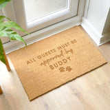 Doormat with 'All guests must be approved by Buddy' text on a wooden floor.