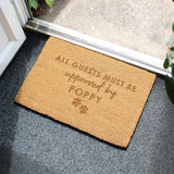 Doormat with 'All guests must be approved by Poppy' text on a gray floor.
