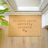 Doormat with text 'All guests must be approved by Jackson' on a wooden floor.