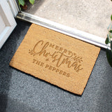 Doormat with 'Merry Christmas The Peppers' text on a gray floor.