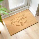 Personalized doormat with 'The Rowe Family Home Sweet Home' text on a wooden floor.