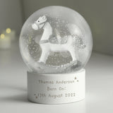 Snow globe with a horse figure and engraved text on a white surface.