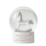 Snow globe with a white horse figurine and engraved text on a white background