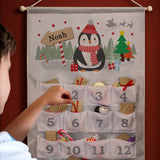 Child interacting with a Christmas-themed advent calendar on a red wall.