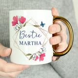 Person holding a mug with floral design and 'Bestie MARTHA' text