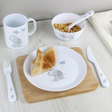 Lifestyle image of personalised 3 piece white plastic cutlery set with hessian elephant design. Pictured alongside matching mug, plate and bowl. All featuring the name Alfie. Plate has on it 2 small triangles of toast and bowl contains both the spoon and some cereal