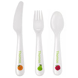 A set of white plastic cutlery including a spoon, fork, and knife, each with the name 'Thomas' and fruit illustrations on the handles. On Plain white background.