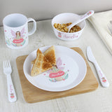 Children's meal set with plate, cup, bowl, and cutlery featuring a fairy design on a wooden table.