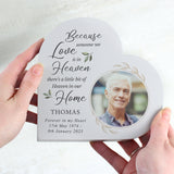 Heart-shaped memorial keepsake with a photo of a man and text about someone being in heaven. Held in an adult females hands
