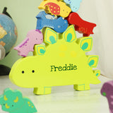 Colorful dinosaur-shaped toy with 'Freddie' on a light surface, globe in the background