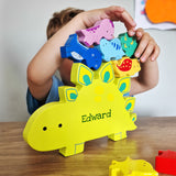Child playing with a colorful dinosaur-shaped puzzle on a wooden table.