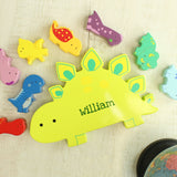 Colorful dinosaur-shaped nameplate with 'william' on a light wooden surface