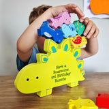 Child playing with a colorful dinosaur-shaped puzzle on a wooden table.