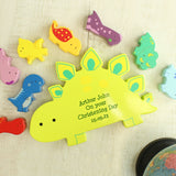 Colourful dinosaur-shaped wooden toy with personalized text on a light background