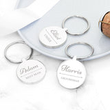 Three silver keychains with engraved names on a marble surface.