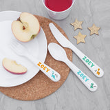 Personalized children's cutlery set with 'ZOEY' on a plate with apple slices and a cup of juice.