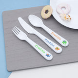Personalized cutlery set with 'Freddie' on a wooden placemat.