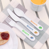 Children's cutlery set with 'Meave' branding on a table with a plate and mug.