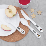 White cutlery set with 'Harry' branding on a table with apples and a cup.