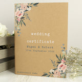 A personalised wedding certificate display book with floral designs on the cover, customized with the names 'Megan & Robert' and a date '17th September 2022'.