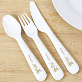 A set of white plastic cutlery featuring a giraffe design on the handles, consisting of a spoon, knife, and fork, presented on a wooden surface.