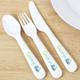 A set of white plastic cutlery including a spoon, fork, and knife, each featuring a patchwork train design and the name 'George' on the handles.