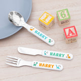 A set of children's cutlery with 'Harry' text and dinosaur graphics on a white background, including a fork, knife, and spoon.
