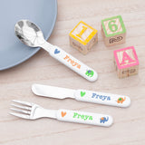 A set of personalized kids' cutlery including a fork, knife, and spoon with animal and letter motifs, designed for dining.