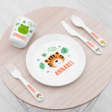 A personalised kids' dining set with jungle animal theme, including a plate with a tiger design, a bowl, a fork, and a spoon laid out on a wooden table.
